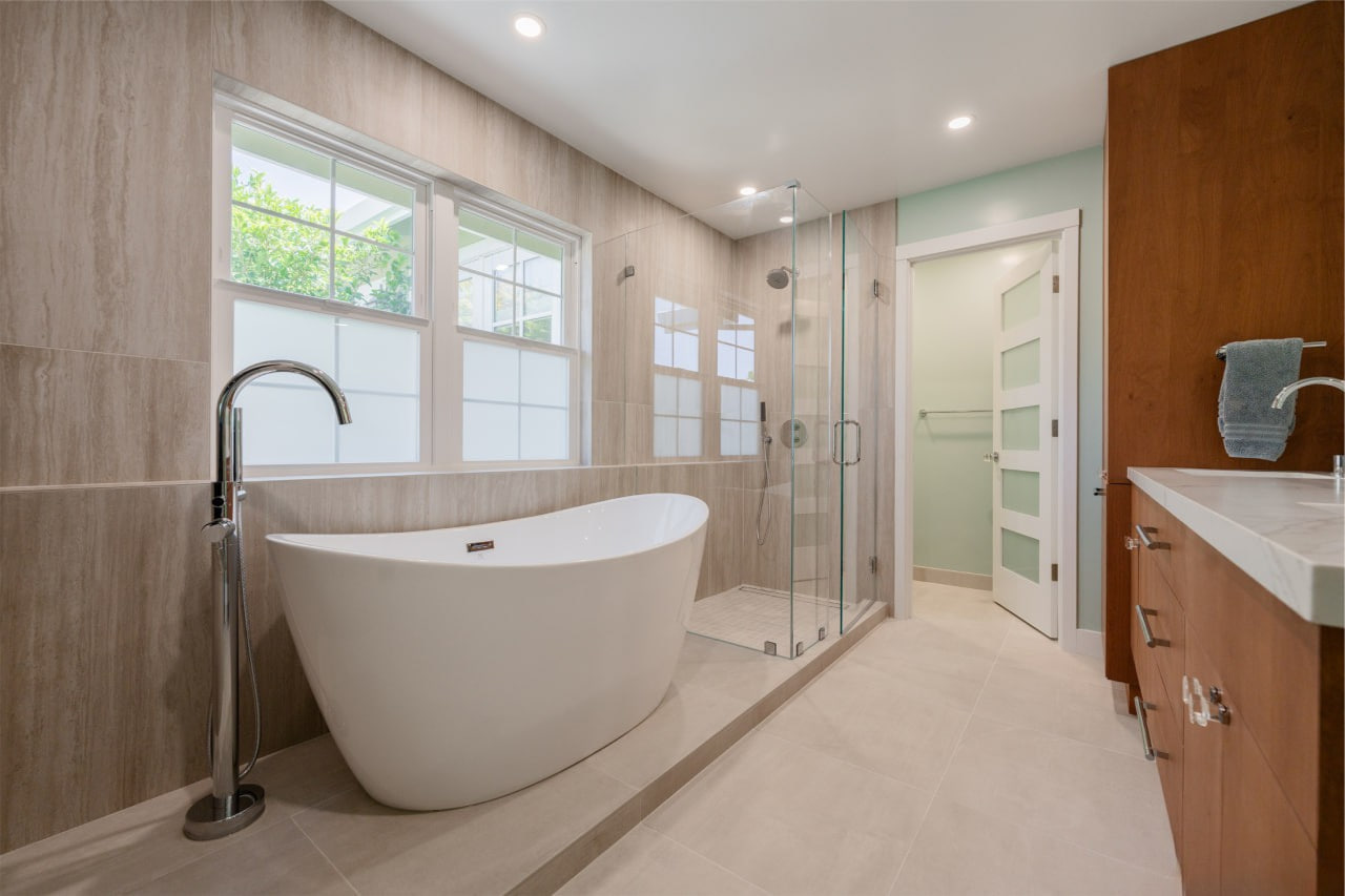 Exceptional bathroom remodeling in San Jose creating spa-like retreat with freestanding tub positioned beneath expansive windows and warm wood ceiling