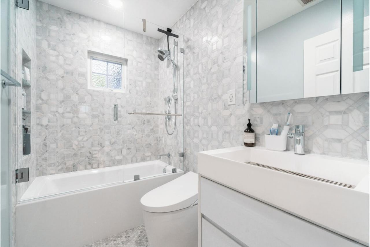 Elegant bathroom featuring premium marble vanity countertops paired with frameless glass shower and modern tub